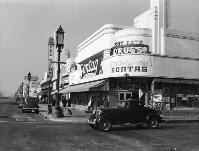 View looking west at the intersection of Wilshire Boulevard and Cloverdale Avenue. The Sontag Drug Store is seen on the northwest corner. Today it is the location of Wilshire Beauty Supply. The sign for the A and P Food Palace can be seen, the grocery store was next-door to Sontag's.